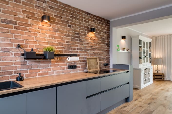Bild einer grauen grifflosen Küche vom Ellerbrock Küchenstudio mit fließendem Übergang zum Wohnbereich